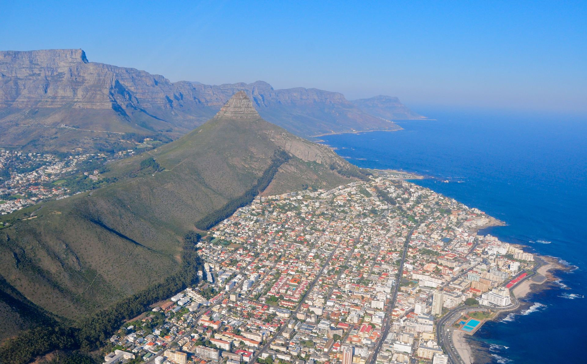 Aerial view of Cape Town along the coast, the city held between mountain and sea.