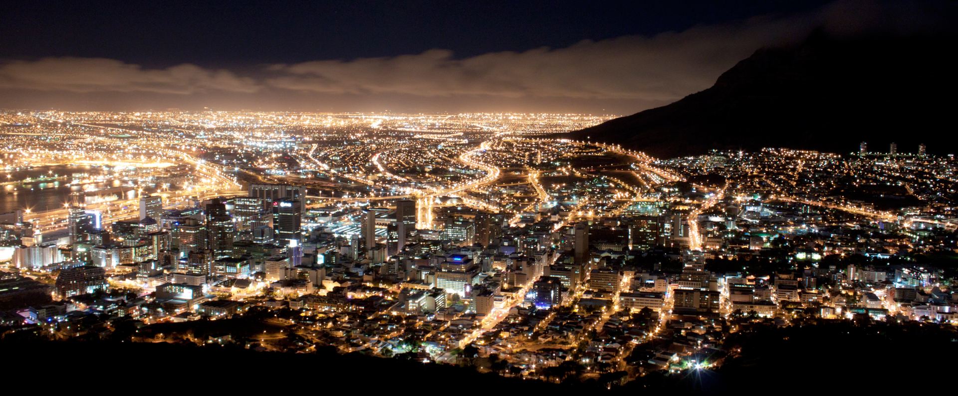 Cape Town at night, the lit city bowl held between the mountain and the sea.